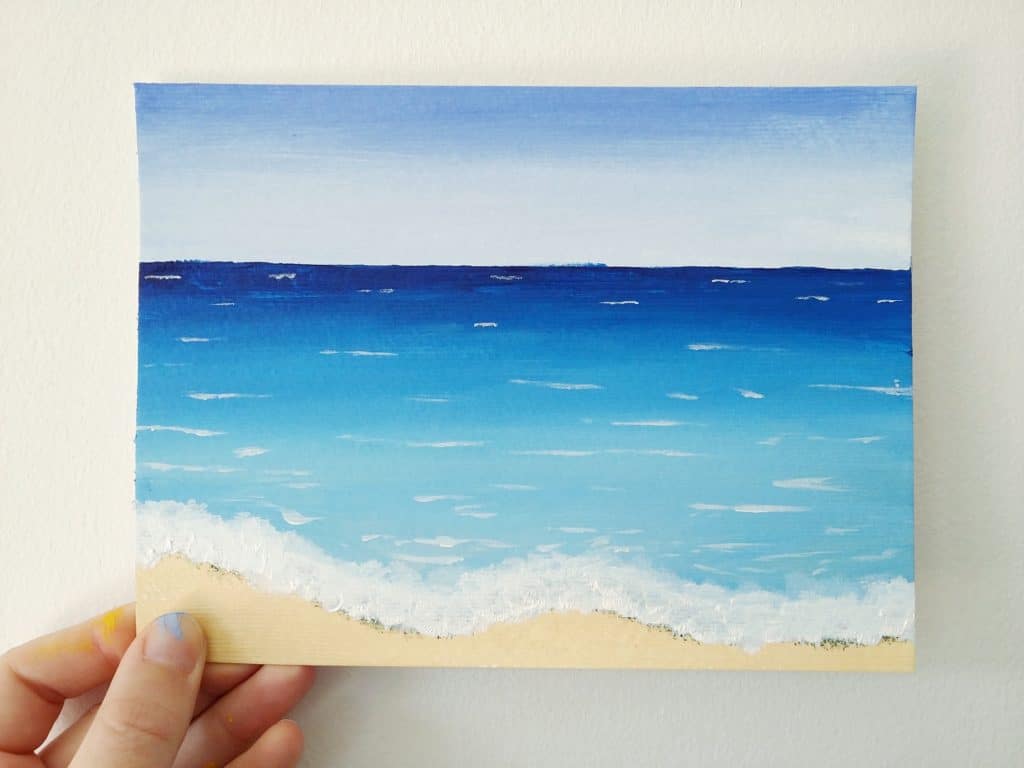 This tutorial for a quick and deceptively simple beach scene painting is a great creative project for the summer. Click through for the steps to paint your own beach!