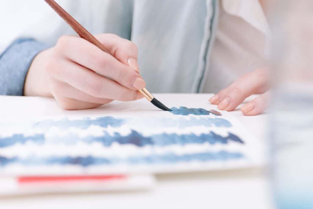 person painting a blue watercolour pattern